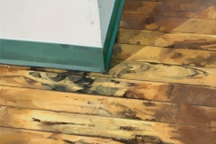 an oil painting on panel, 23.5 x 23.5 inches, painted in 2017. It is a painting of a wood floor where it meets the positive corner of two walls meeting.