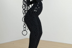 Female figure with fully pierced form and hands poised in air, flat black.