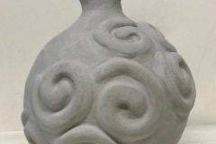 Round bellied vase form ending in a wide lip and embossed spirals on surface.