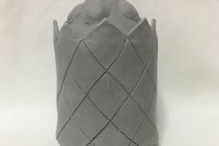 A jar form with criss cross lines and an ornate lid with bubble forms and faceted knob.