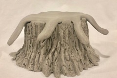 Jar sculpted in the shape of a sawed tree trunk with an implied liquid lid.