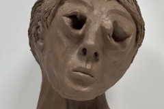 Expressive self-portrait bust with cut out eyes and tilted head.