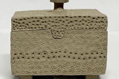 Rectangular box with heavily textured surface set on small feet.