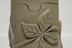 Round Jar with flower appliqué on surface.