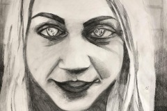 “All At Once” is a self portrait depicting a woman’s head, seemingly floating her body. There is little value range, an almost black and white high contrast drawing. Drawn into the irises of her eyes are various symbols, a peace sign, a Cross and the Star of David to name a few.