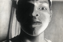 A self portrait with clean line markings, featuring a young man with hat backwards, and half of his face brightly lit. the other half in shadow. he is looking down at the viewer.
