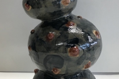 Tall Jar form create with repeated round forms and embellished with round red balls on surface, glazed dark blue.