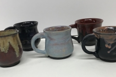 5 handled mugs, glazed brown, blue, black and red.