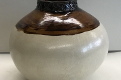 Sphere shaped vessel glazed brown at the top cream colored at the bottom.