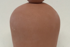 Terra cotta colored jar form with an eyeball lid.
