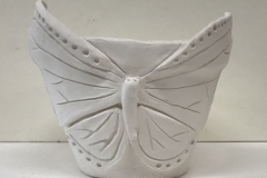 flower pot form with butterfly form sculpted on surface.
