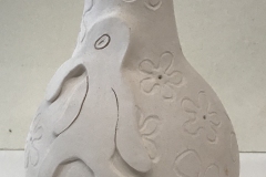 vase form with flowers and a squidward carved and applied to the surface.