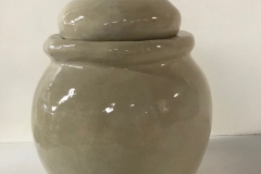 large rounded jar form with round knob on lid glazed cream color.
