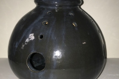 Round form with circular cut outs, glazed black.