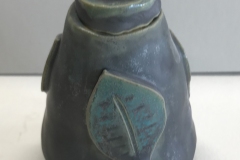 small jar with leaf pattern on surface.
