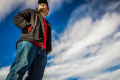 image of a man standing up taken from the ground, the blue cloudy sky is the background.