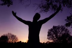 image of a mans silhouette with arms raised up.
