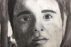 Self portrait of a man looking past the viewer. On one side of the face is flourishing forest, the other side of his face is a wasteland of stumps.