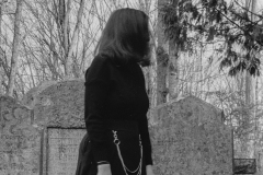 black and white image of a woman dressed in black in a graveyard.