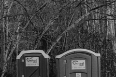 black and white image of two port-o-potties.